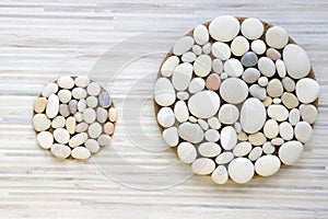 Two magic stone circles shape on white and grey stripped background, light pebbles, mandalas made of stones