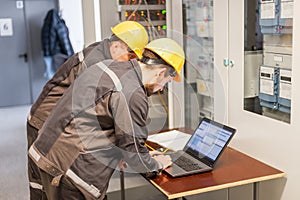 Two maintenance engineers inspect relay protection system with l