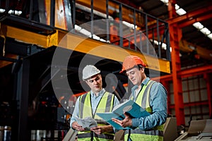 Two Maintenance engineers men and women inspect relay protection system with checklist document . They work a heavy industry