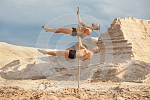 Two male acrobats are dancing on a pylon.