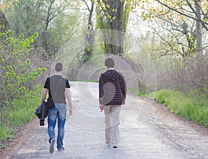 Two male adult friends walking in nature on sunny spring day