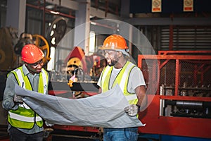 Two male African American maintenance engineers, are working and looking at blueprint