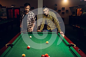 Two male billiard players with cue, poolroom