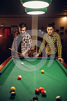 Two male billiard players with cue, poolroom