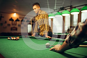 Two male billiard players with cue at the table