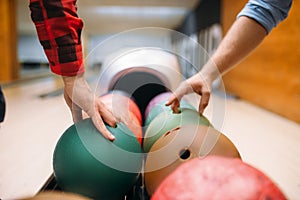 Two male bowlers takes balls from feeder