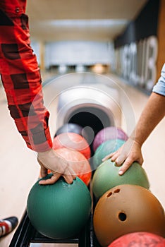 Two male bowlers takes balls from feeder