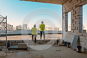 Two male builders at a construction site. Men looking into the distance to the panorama of the city. Building, development, teamwo