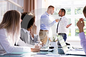 Two Male Colleagues Fighting In Office photo