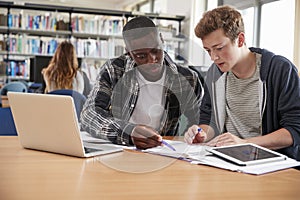 Two Male College Students Collaborating On Project In Library