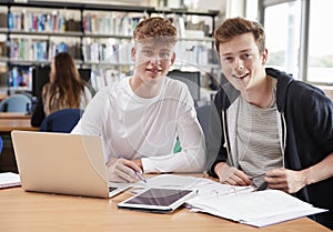 Two Male College Students Collaborating On Project In Library