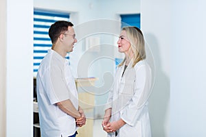 Two Male and Female Doctors or Nurses Standing Inside Hospital Building.