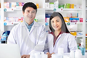 Two Male and female pharmacists smiling happy to Service in drugstore Thailand