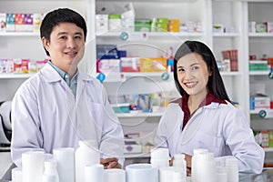 Two Male and female pharmacists smiling happy to Service in drugstore Thailand health care