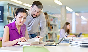 Two male and female students studying together in library