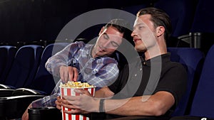 Two male friends laughing while watching comedies at the cinema
