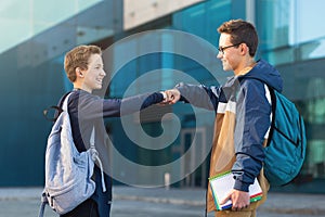 Two male friends meeting oudoors, teenagers greeting each other