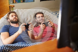 Two Male Friends In Pajamas Playing Video Game Together