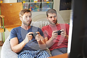 Two Male Friends In Pajamas Playing Video Game Together