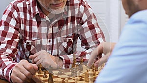 Two male friends playing chess, thinking over strategy, common hobby, close-up