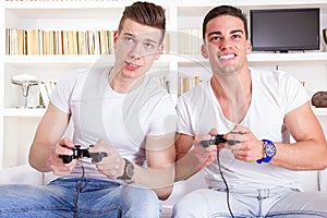 Two male friends playing video game with controllers