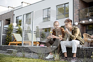 Two male friends talking on a porch of the country house