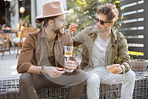 Two male friends talking on a porch of the country house