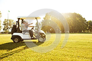 Two male golfers driving in a golf cart