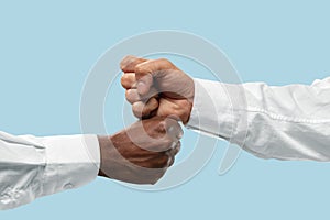 Two male hands competion in arm wrestling isolated on blue studio background