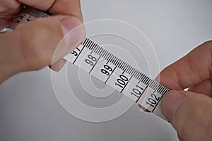 Two male hands holding a tape measure measuring length in centimeters and meters