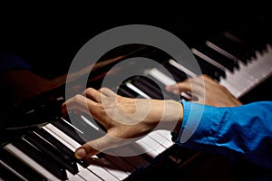 Two male hands on the piano. palms lie on the keys crosswise and play the keyboard instrument in the music school. student learns