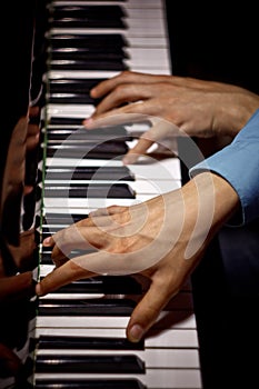Two male hands on the piano. palms lie on the keys crosswise and play the keyboard instrument in the music school. student learns
