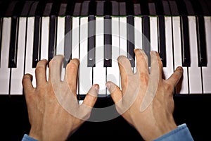 Two male hands on the piano. palms lie on the keys and play the keyboard instrument in the music school. student learns to play.