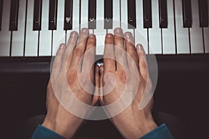 Two male hands on the piano. palms lie on the keys and play the keyboard instrument in the music school. student learns to play.