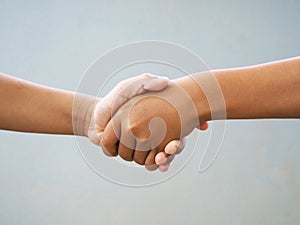 Two male hands shaking isolated on blue studio background. Socia concept.