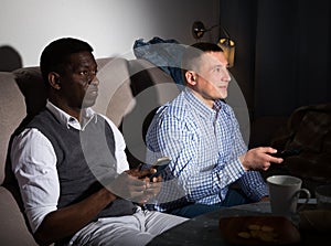 Two male interracial friends watching football game