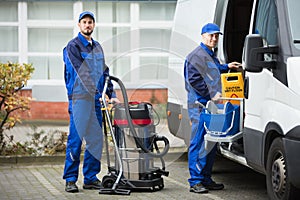 Two Male Janitor Unloading Cleaning Equipment From Vehicle