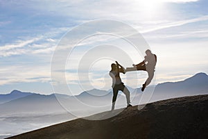 Two male kickboxers fighting on a mountain top