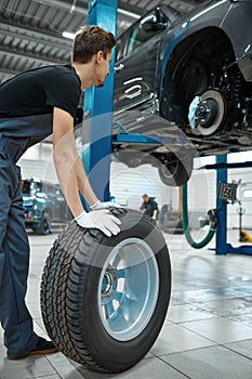 Two male mechanics fixes wheel, car service