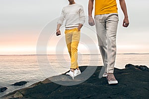 Two male models wearing fashionable spring summer outfit with colorful pants, t-shirt, sweater and shoes walking outdoors