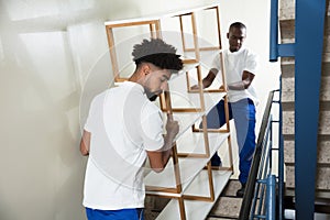 Two Male Movers Carrying The Empty Shelf At Home photo