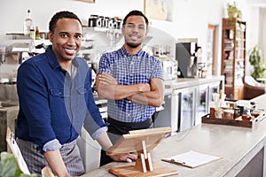 Two male owners behind the counter at their coffee shop