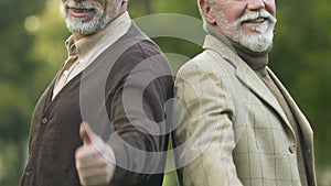 Two male pensioners showing thumbs-up, happy and secure old age, social security