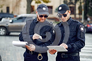 Two male police officers inspect car parking