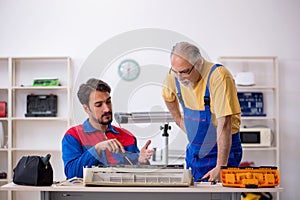 Two male repairmen repairing air-conditioner