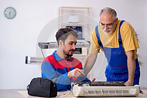 Two male repairmen repairing air-conditioner