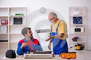 Two male repairmen repairing air-conditioner