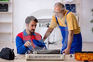 Two male repairmen repairing air-conditioner