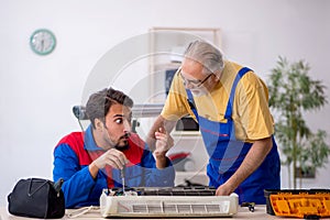 Two male repairmen repairing air-conditioner photo