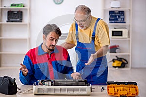 Two male repairmen repairing air-conditioner photo